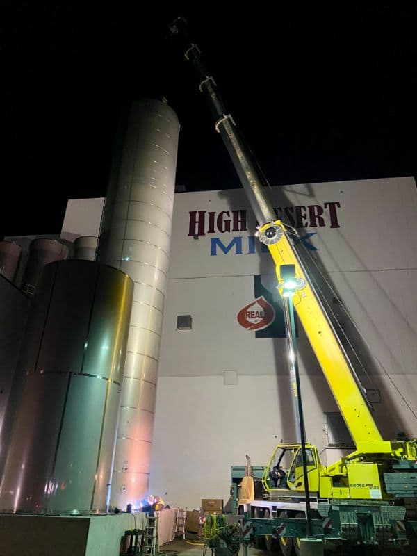 Field crew working beside a tall stainless process vessel